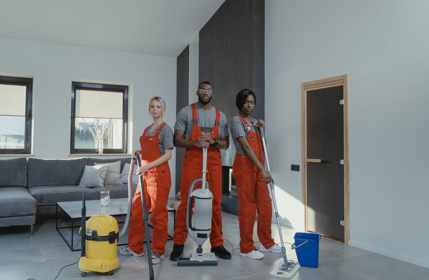 Reinigungsteam mit Sauger, Mopp und Eimer in einer Wohnung